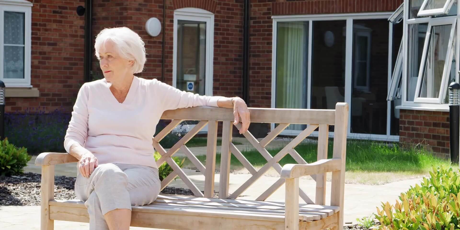 Additional Care Senior resident sitting on a wooden bench