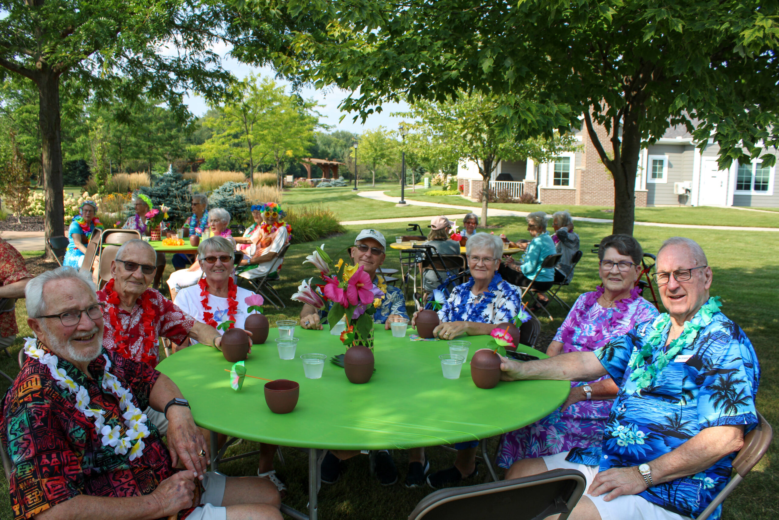 WP Luau – 41 Seniors sitting around a table outside, enjoying a luau event.